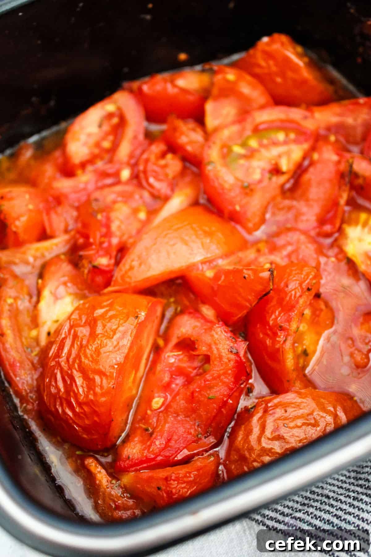 Close-up of a baking dish with roasted tomatoes inside.