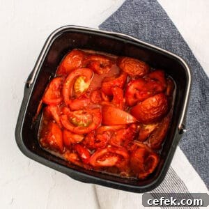 A black pan with roasted tomatoes in it on a white and blue surface.
