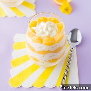 A lemon cheesecake cup - layered cheesecake in a stemless wine glass, on a light purple background.