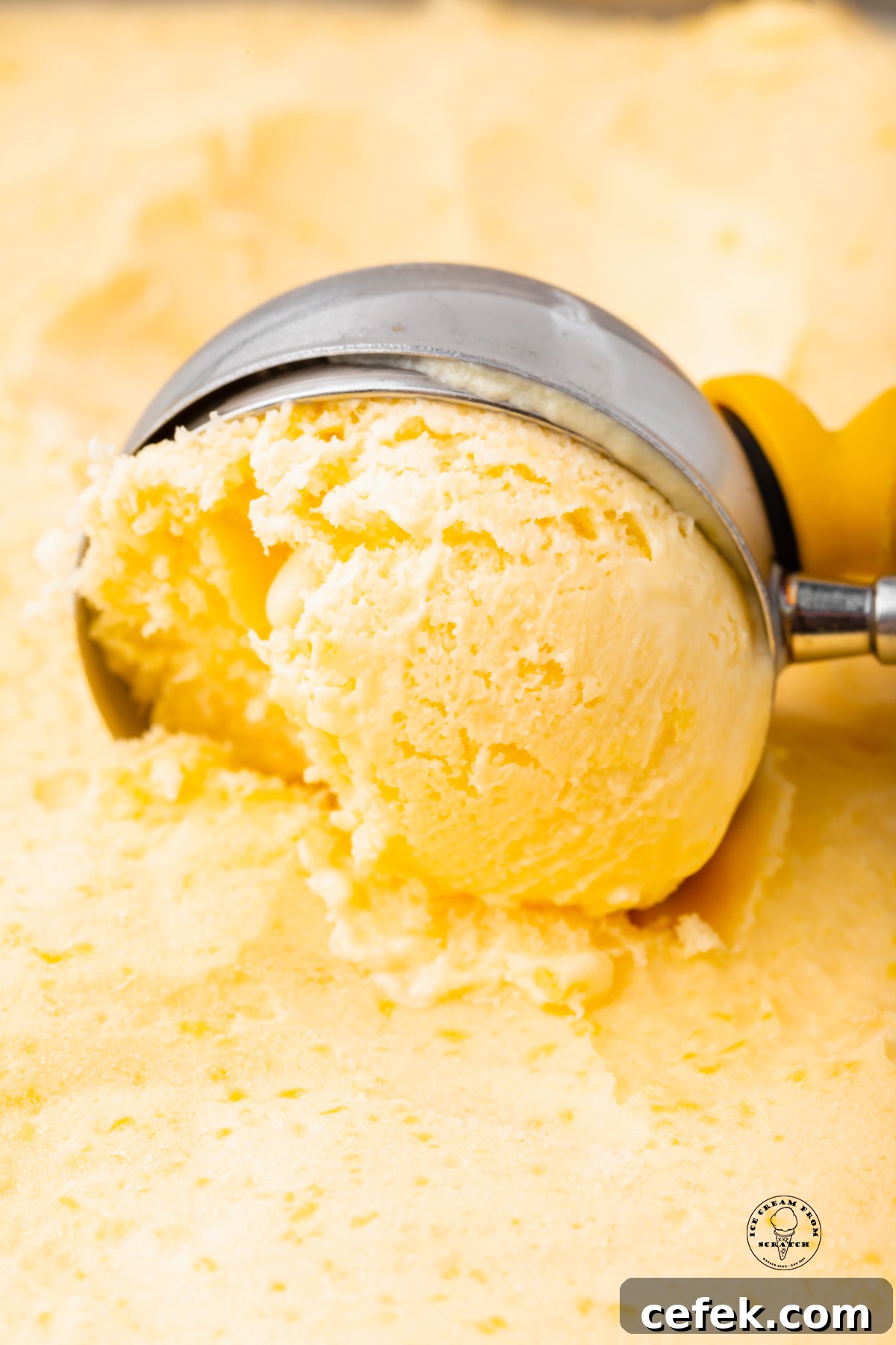 an ice cream scoop pulling through mango gelato, close up shot.