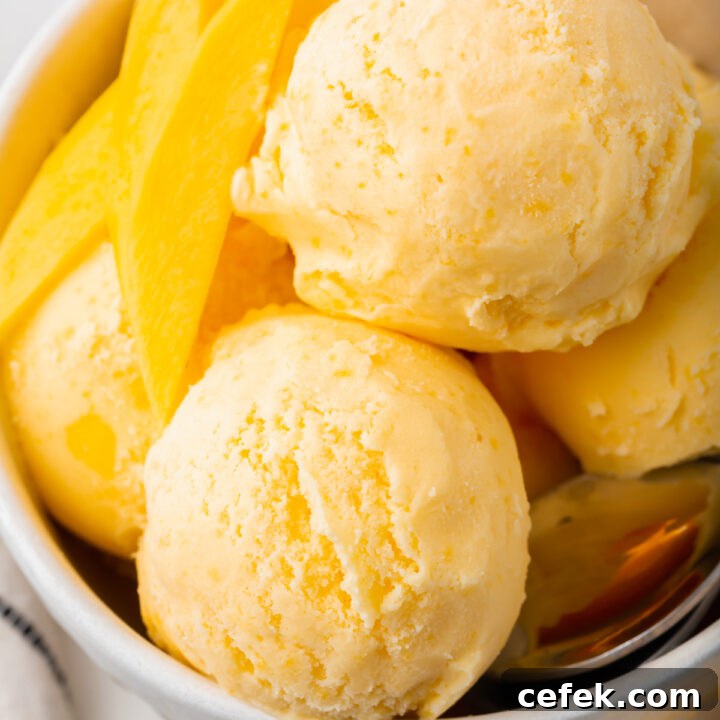 a bowl filled with scoops of mango gelato and mango slices.