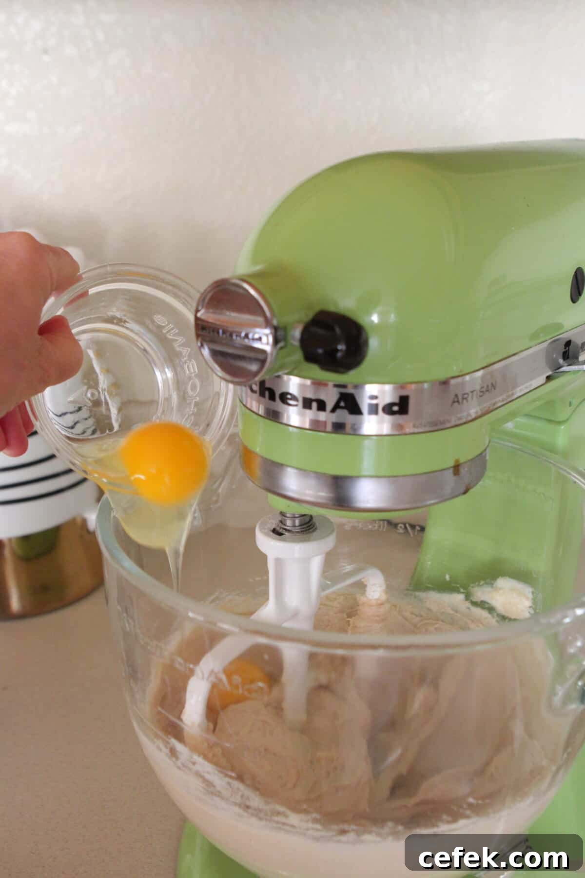 pouring eggs into stand mixer for cookie dough