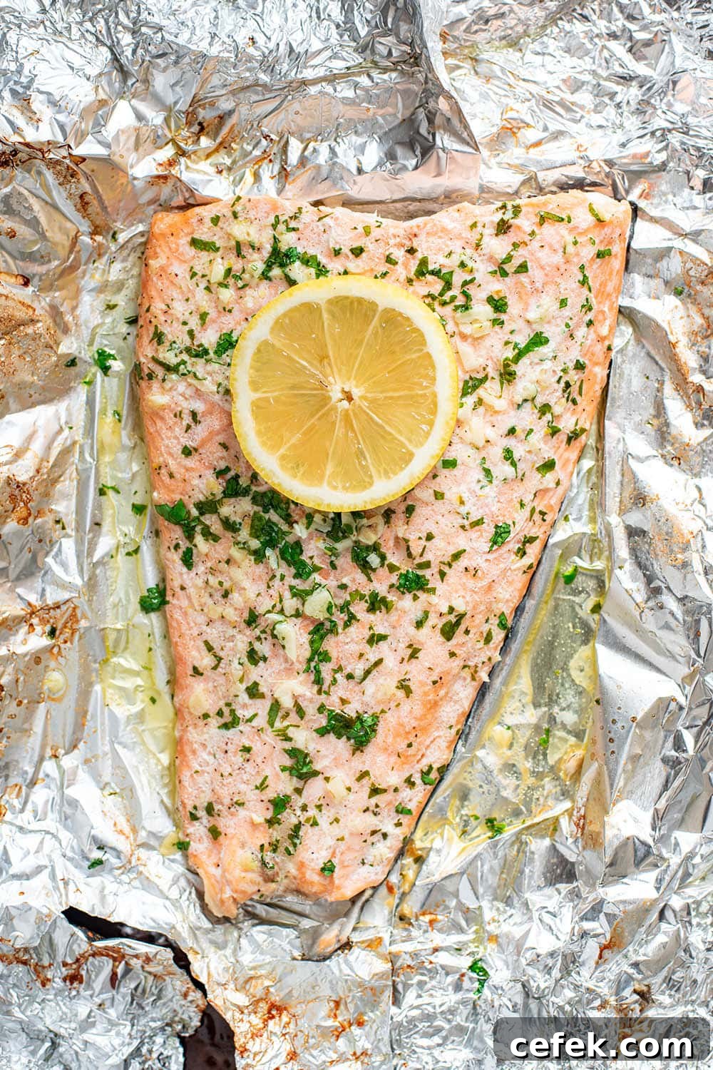 Finished garlic butter steelhead trout topped with a lemon wheel and fresh herbs.