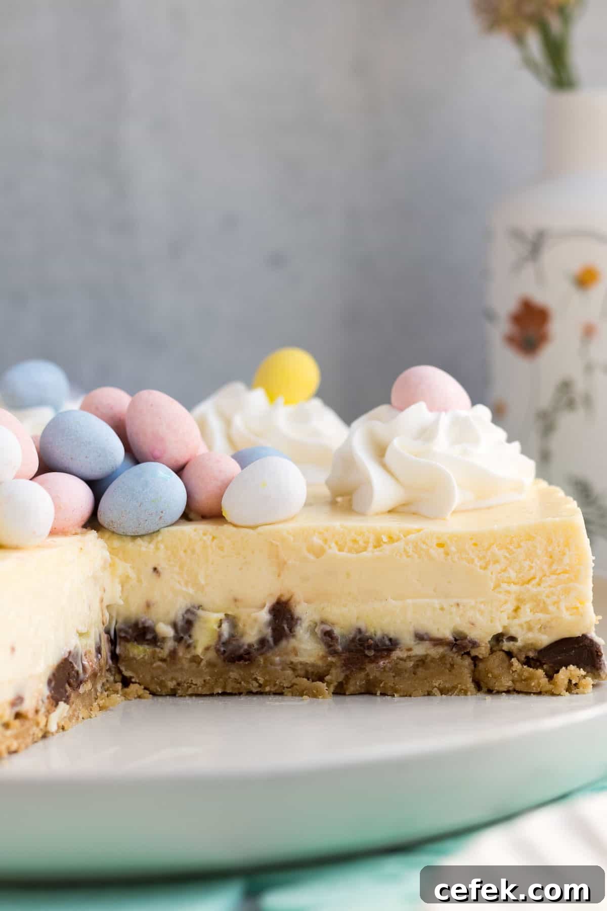 close up of an Easter egg cheesecake on a gray plate with a piece cut out showing the inside of the cheesecake