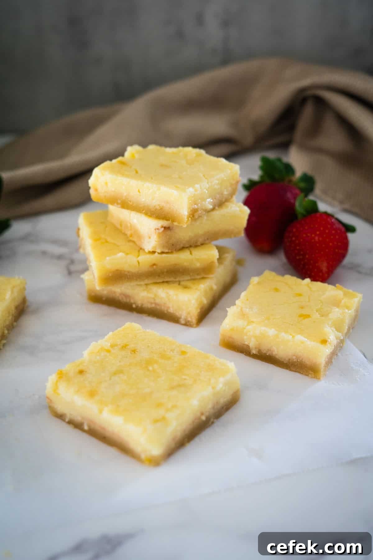 A stack of keto lemon bars with strawberries on top.