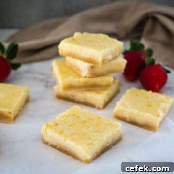 A stack of keto lemon bars adorned with fresh strawberries on top.