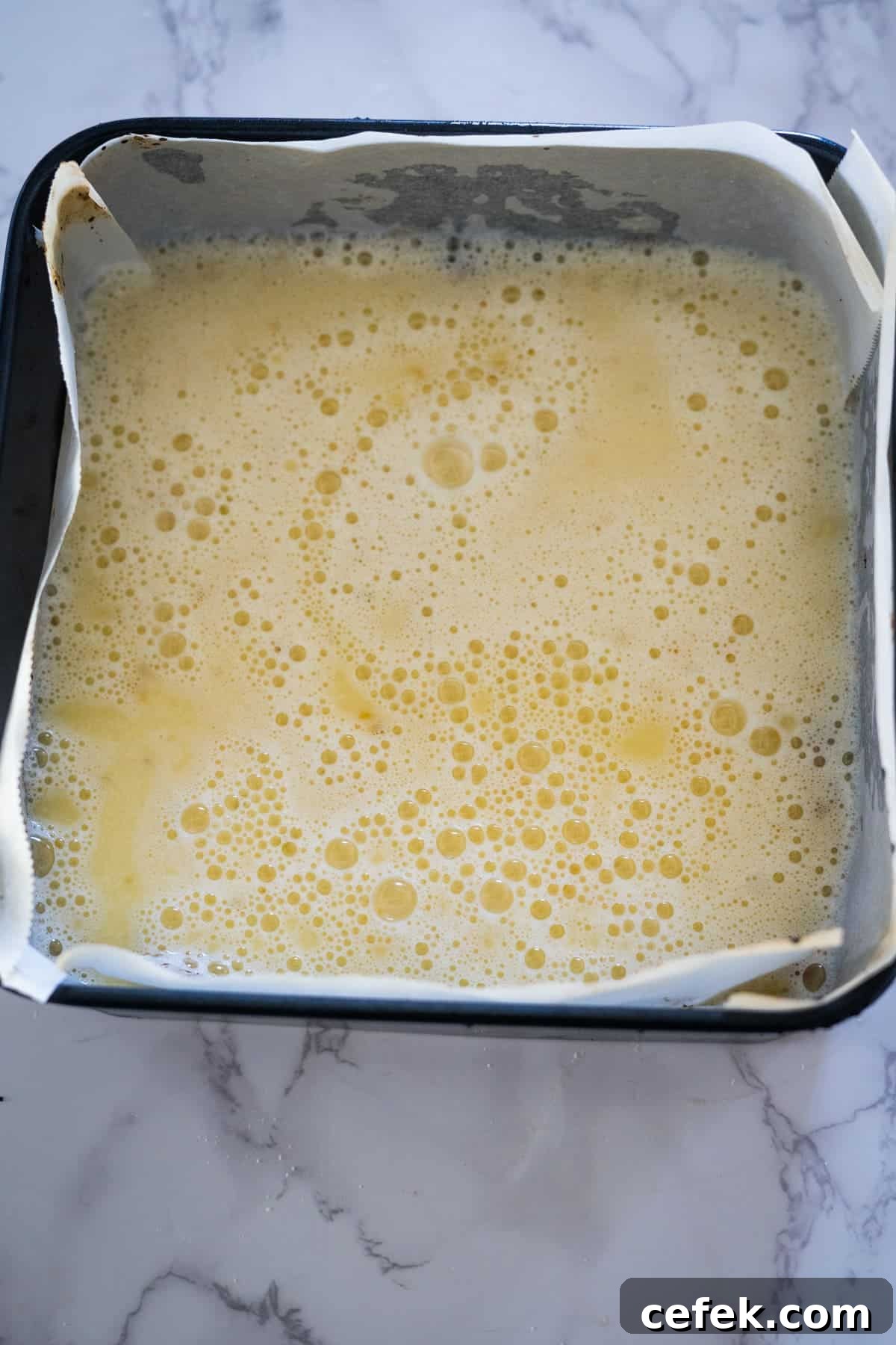 A pan of food with a white paper and yellow liquid.