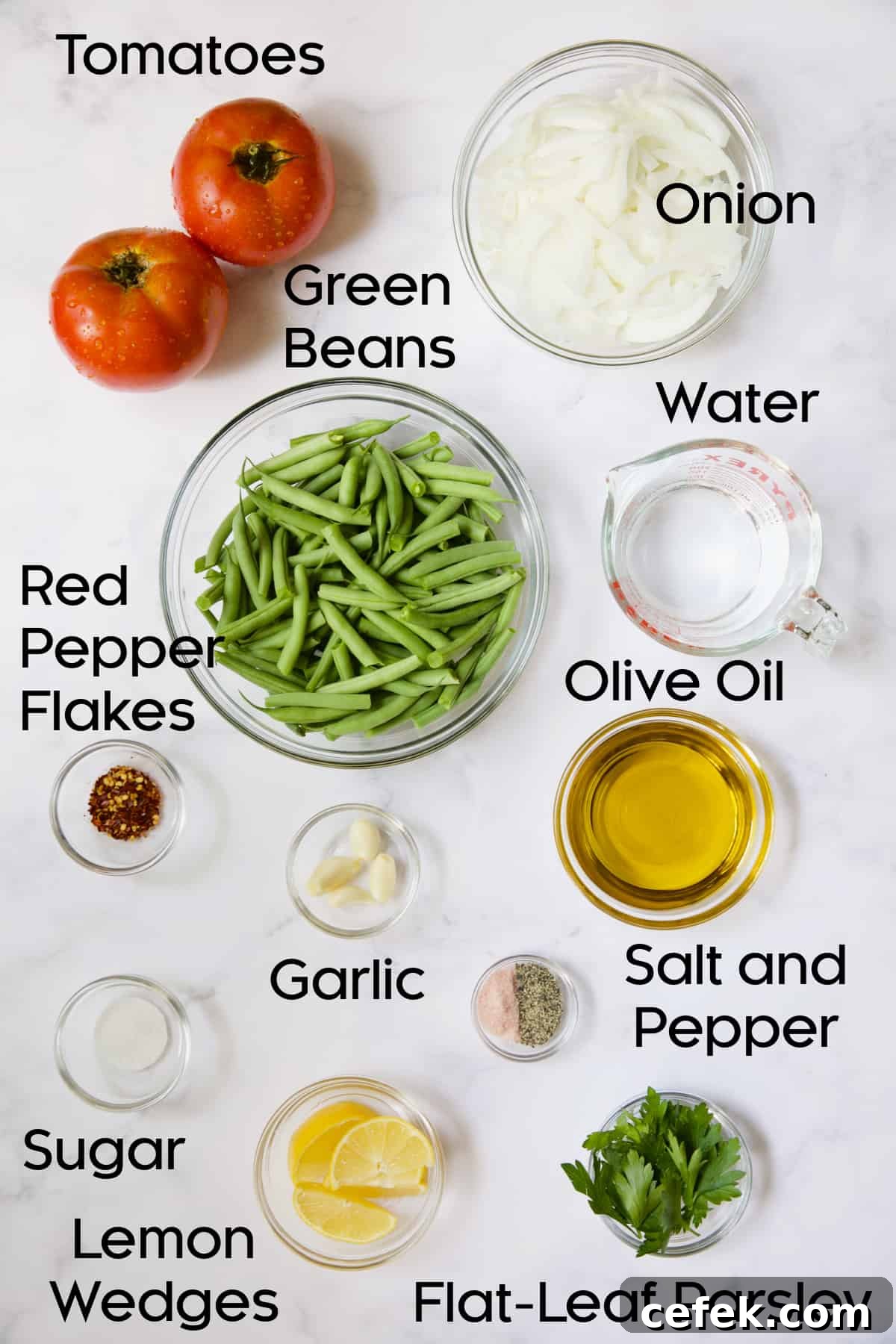 Ingredients for Mediterranean Braised Green Beans with Tomatoes in glass bowls.