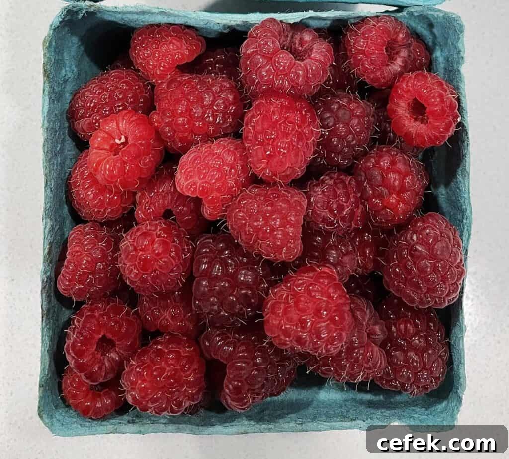 A blue berry basket full of freshly diced raspberries.