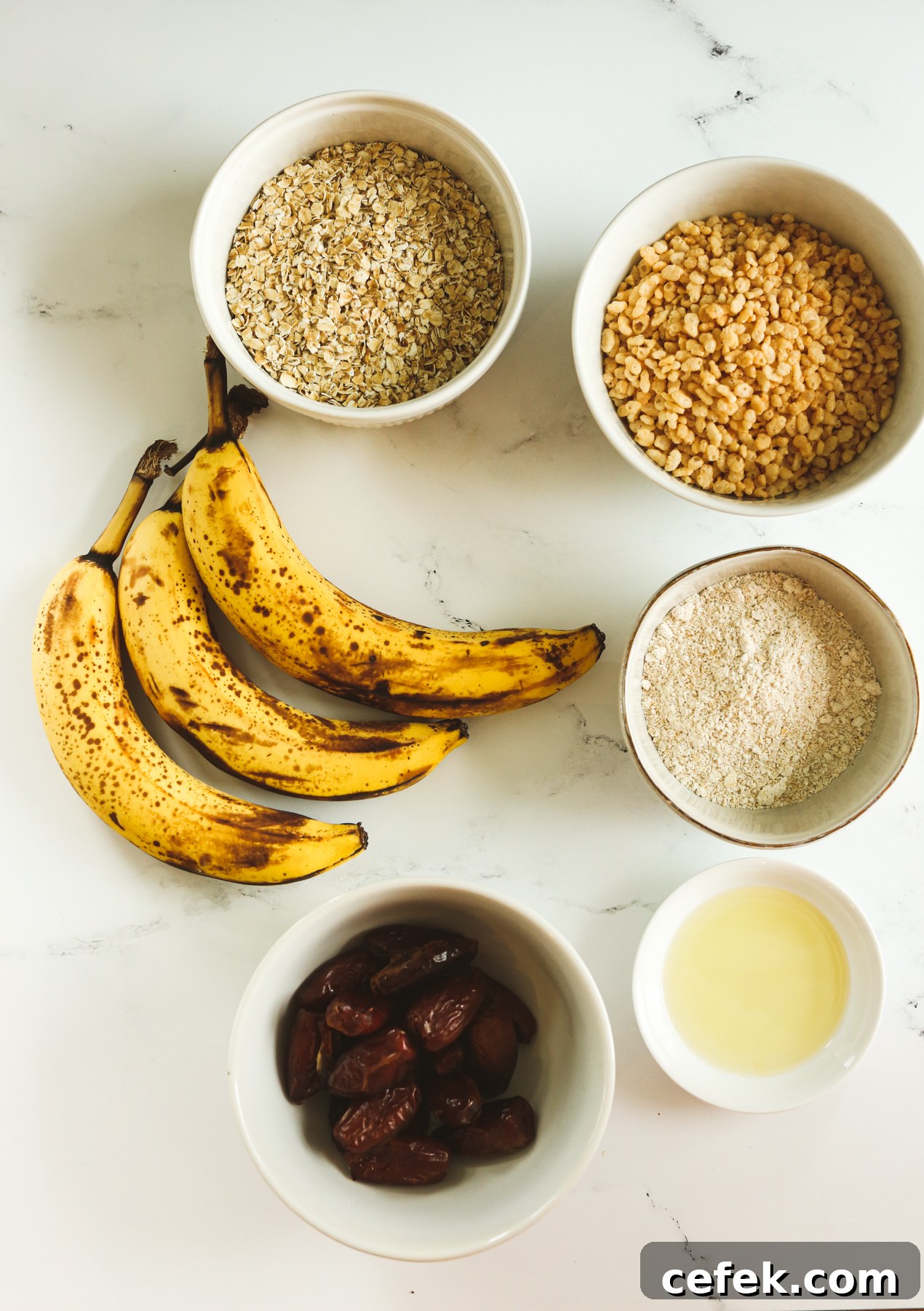 recipe ingredients overhead shot--bananas, bowls with oats, oat flour, dates, brown rice crisp cereal, and oil