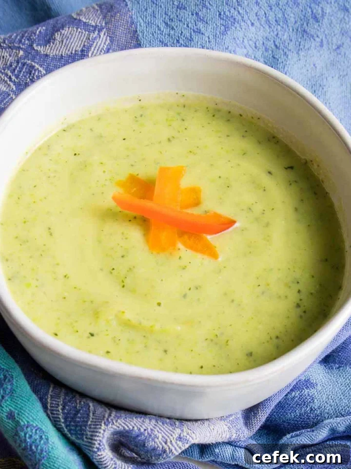 Light green creamy soup with red pepper slices as garnish.