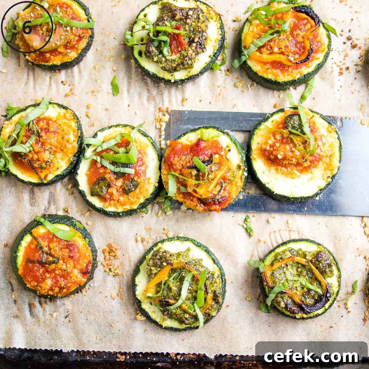 Zucchini Pizza Bites with pesto or marinara and assorted toppings, on a baking tray.