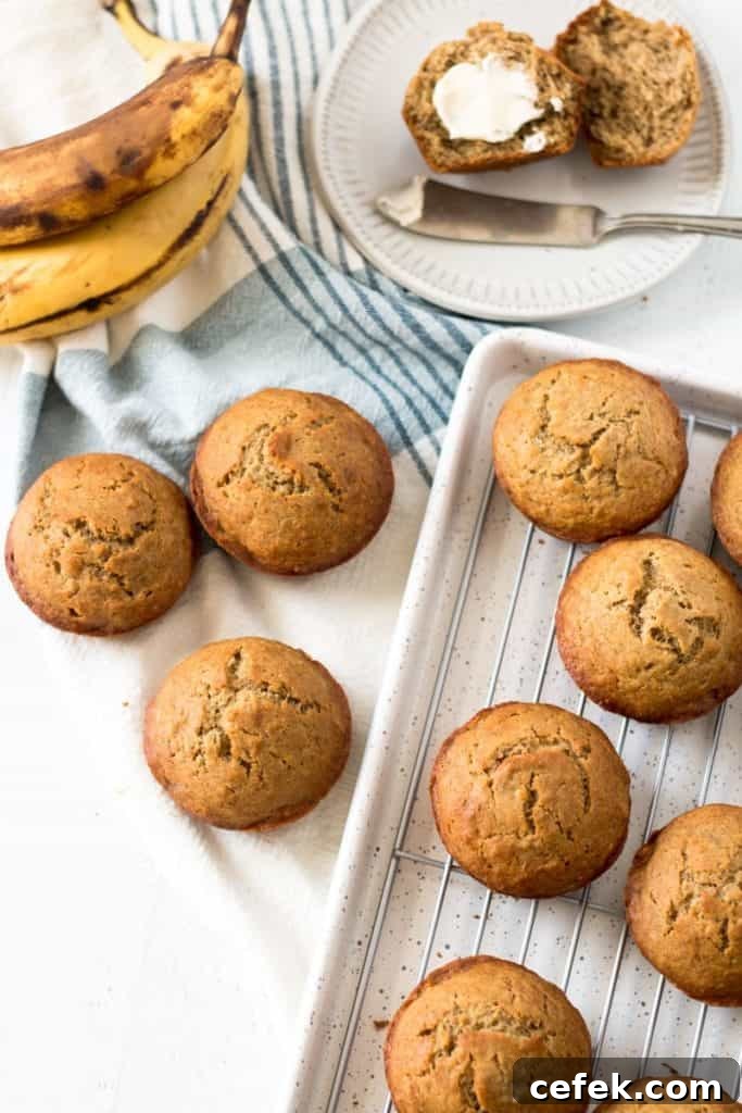 Gluten free banana muffins, one with butter, ripe bananas in background.
