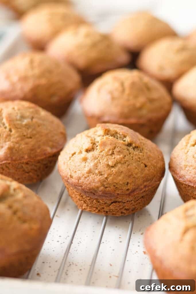 Gluten free whole grain banana muffins on a wire rack over a speckled baking sheet.