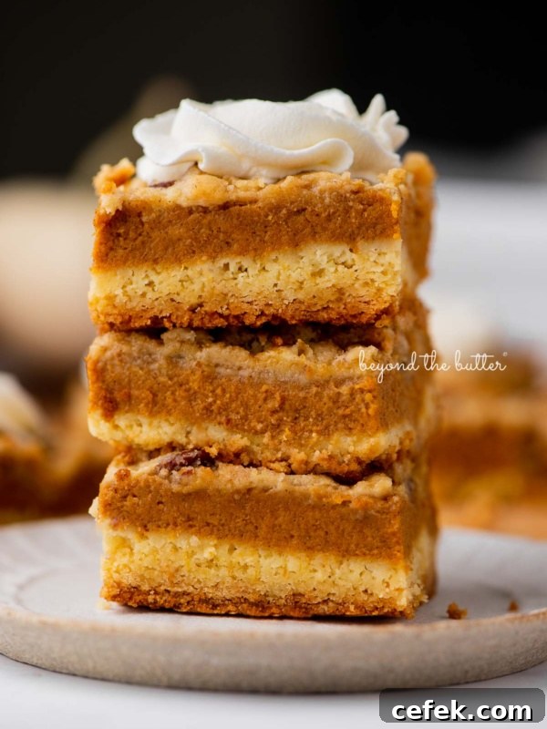 Stack of three pumpkin pie cake bars on a parchment paper lined bottom.