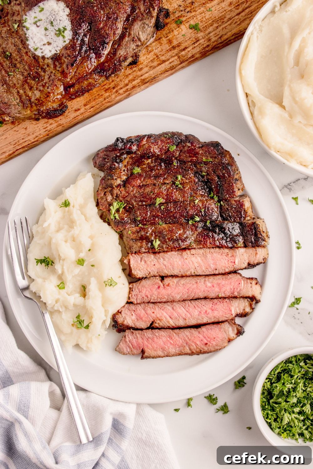 Grilled Ribeye Steak on plate with some mashed potatoes to side all garnished with parsley 