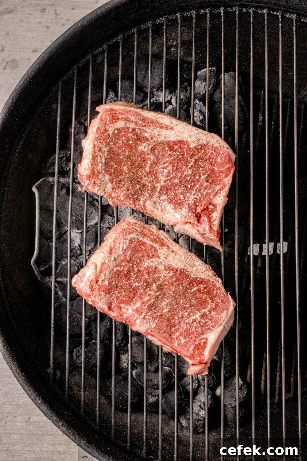 raw Ribeye Steaks on a charcoal grill