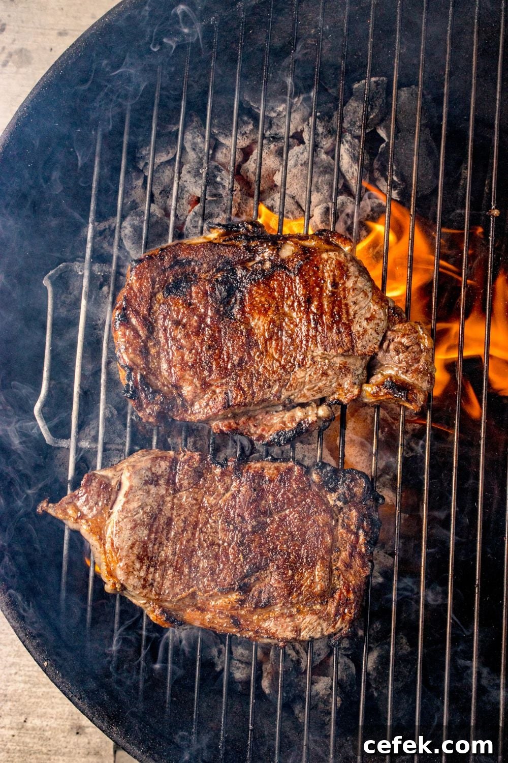 Grilled Ribeye Steaks cooking on a charcoal grill 