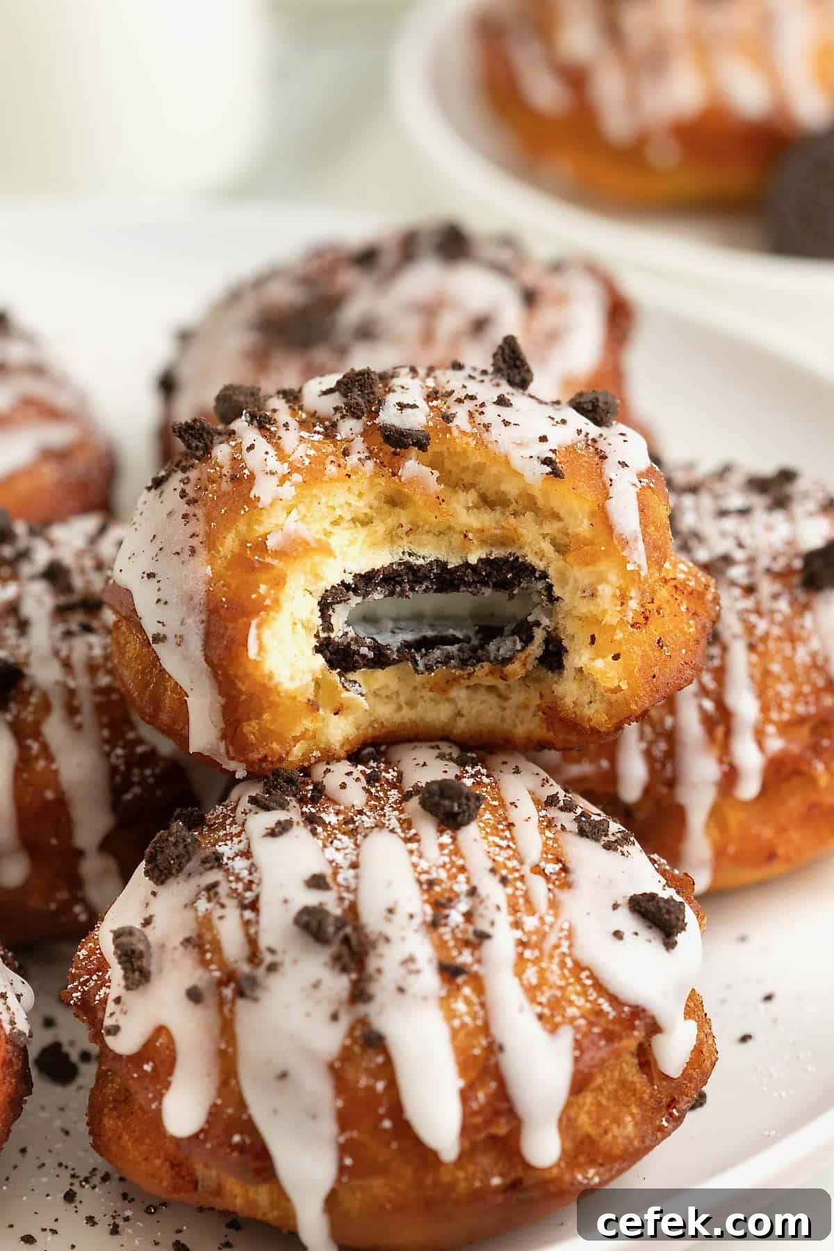 A white rimmed plate holding three fried cinnamon rolls with Oreos in the middle. The one on top is cut open to reveal the Oreo cookie inside.