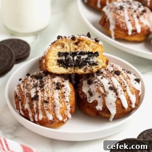 A white rimmed plate holding three fried cinnamon rolls with Oreos in the middle. The one on top is cut open to reveal the Oreo inside.