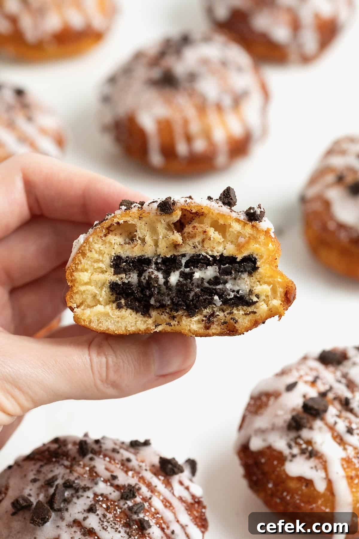 A hand holding a cinnamon roll fried Oreo with a bite out of it.