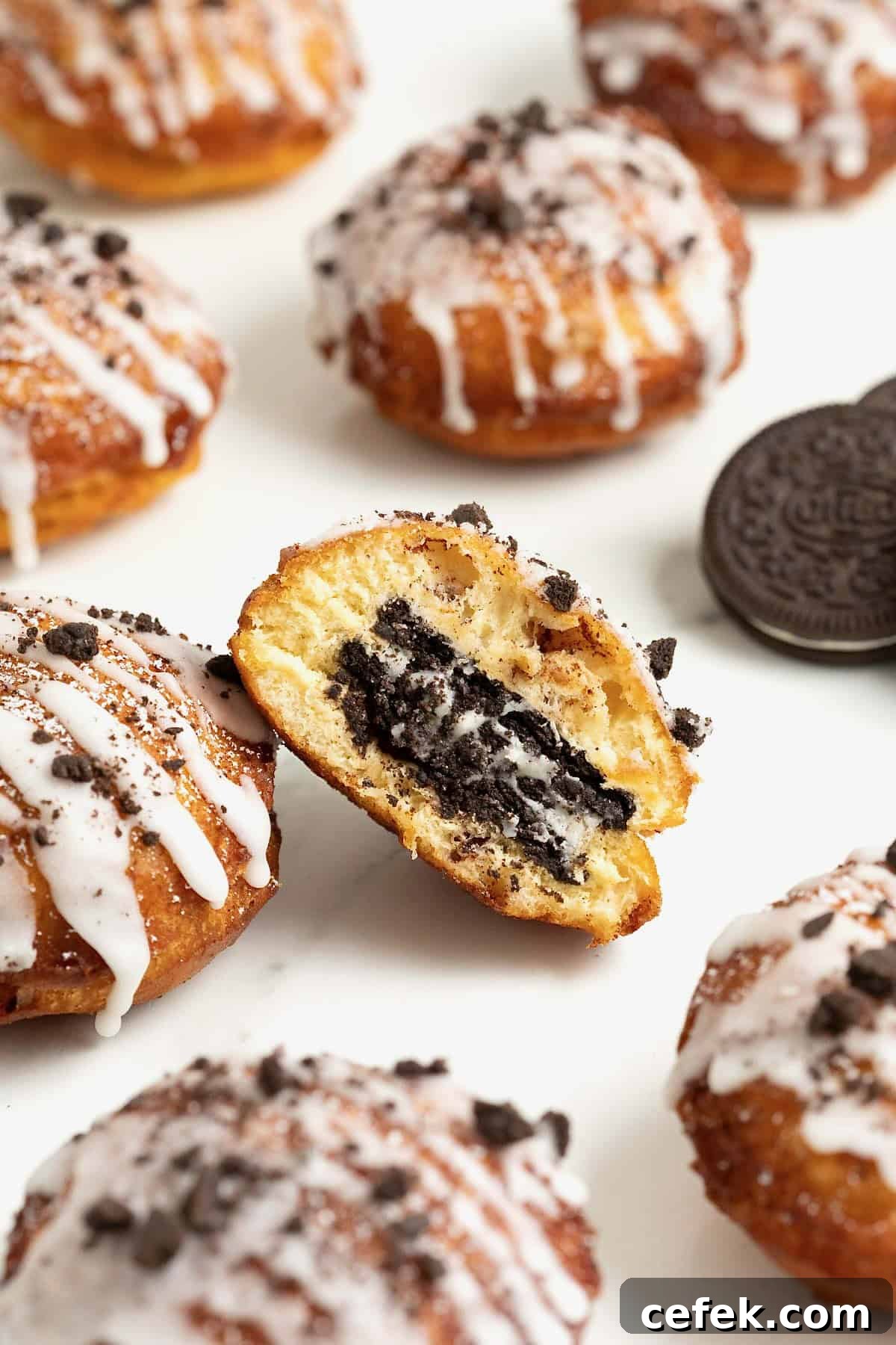 Six cinnamon roll fried Oreos on a white marble counter. The center one is cut in half to show the Oreo inside.