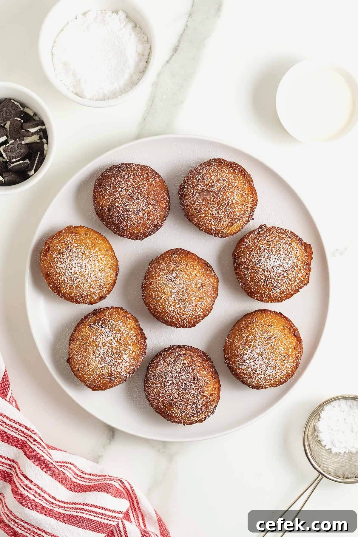 A white rimmed plate filled with 8 cinnamon roll fried Oreos dusted with powdered sugar.