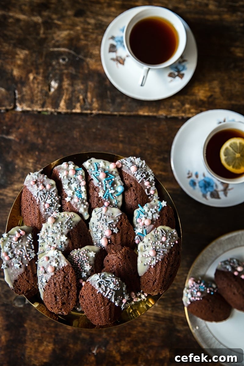 Top down of a plate of Chocolate Madeleines with cups of tea