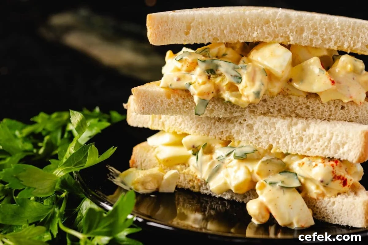 An egg salad sandwich on a reflective platter.