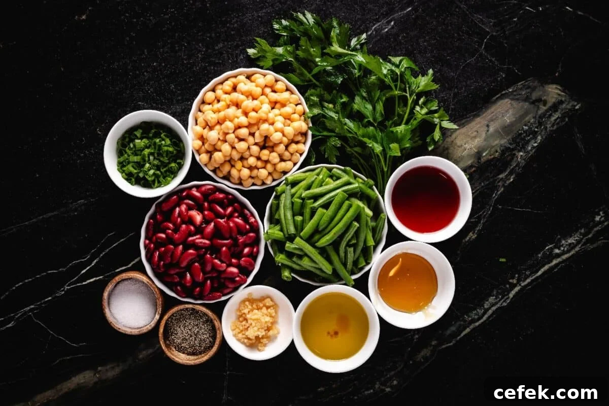 Various beans and liquids in glass bowls on a countertop surrounded by fresh herbs.