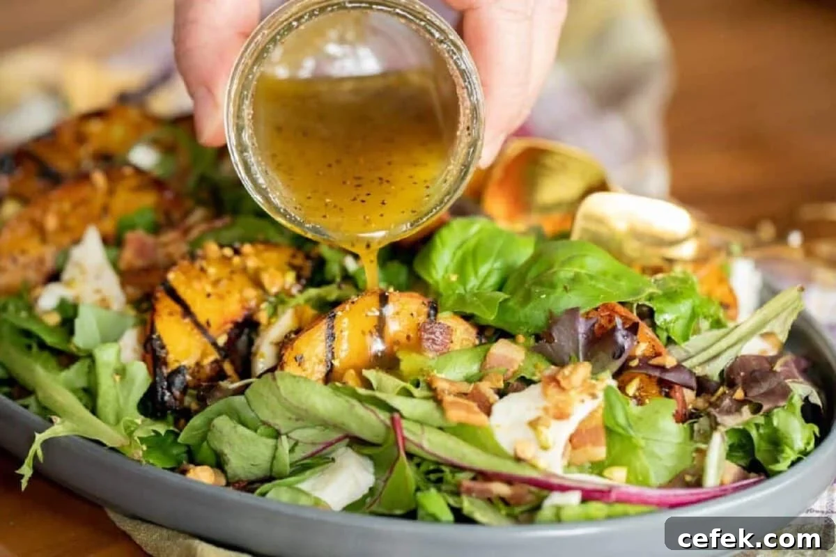A green salad with grilled peaches being drizzled with dressing from a jar.