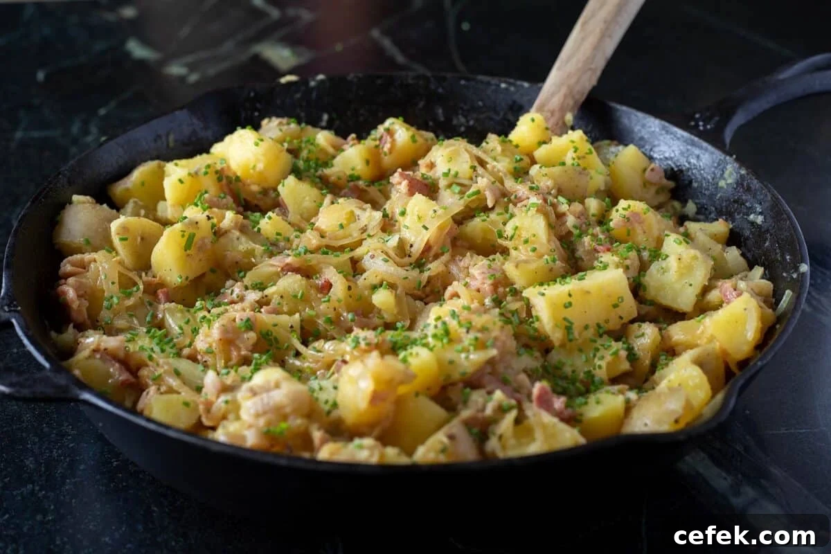 A wooden spoon stirring potatoes and bacon in a cast iron skillet.