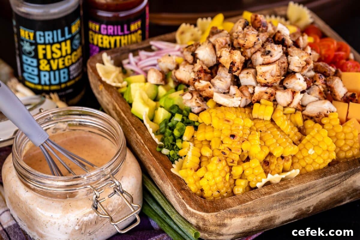 Grilled chicken, corn, and other ingredients on a wooden cutting board next to a jar of sauce.