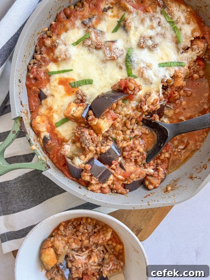 Eggplant parmesan in a skillet with a large serving spoon resting in it