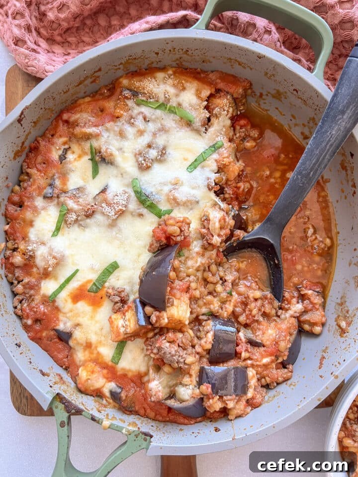 Eggplant parmesan in a skillet with a large serving spoon resting in the skillet