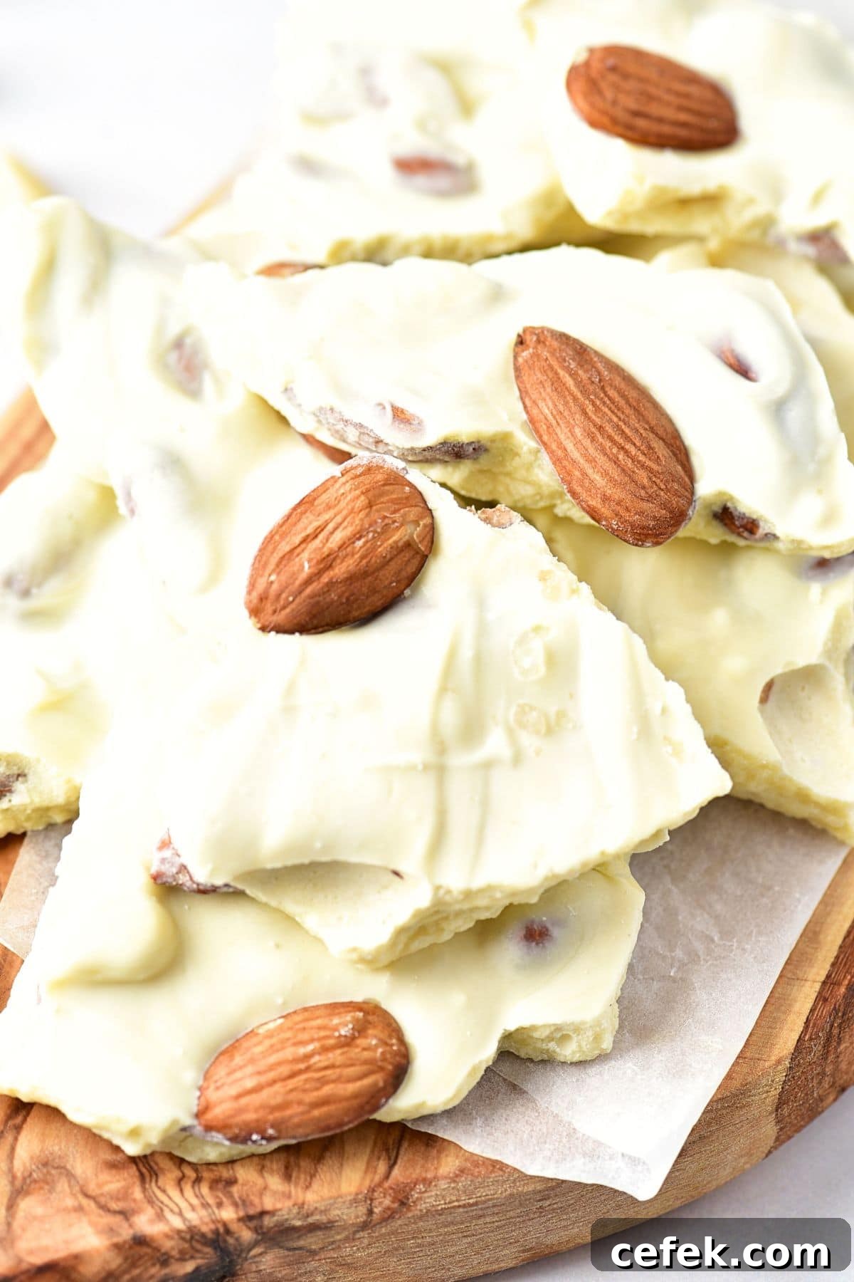 Up close view of almond white chocolate bark on wooden board.