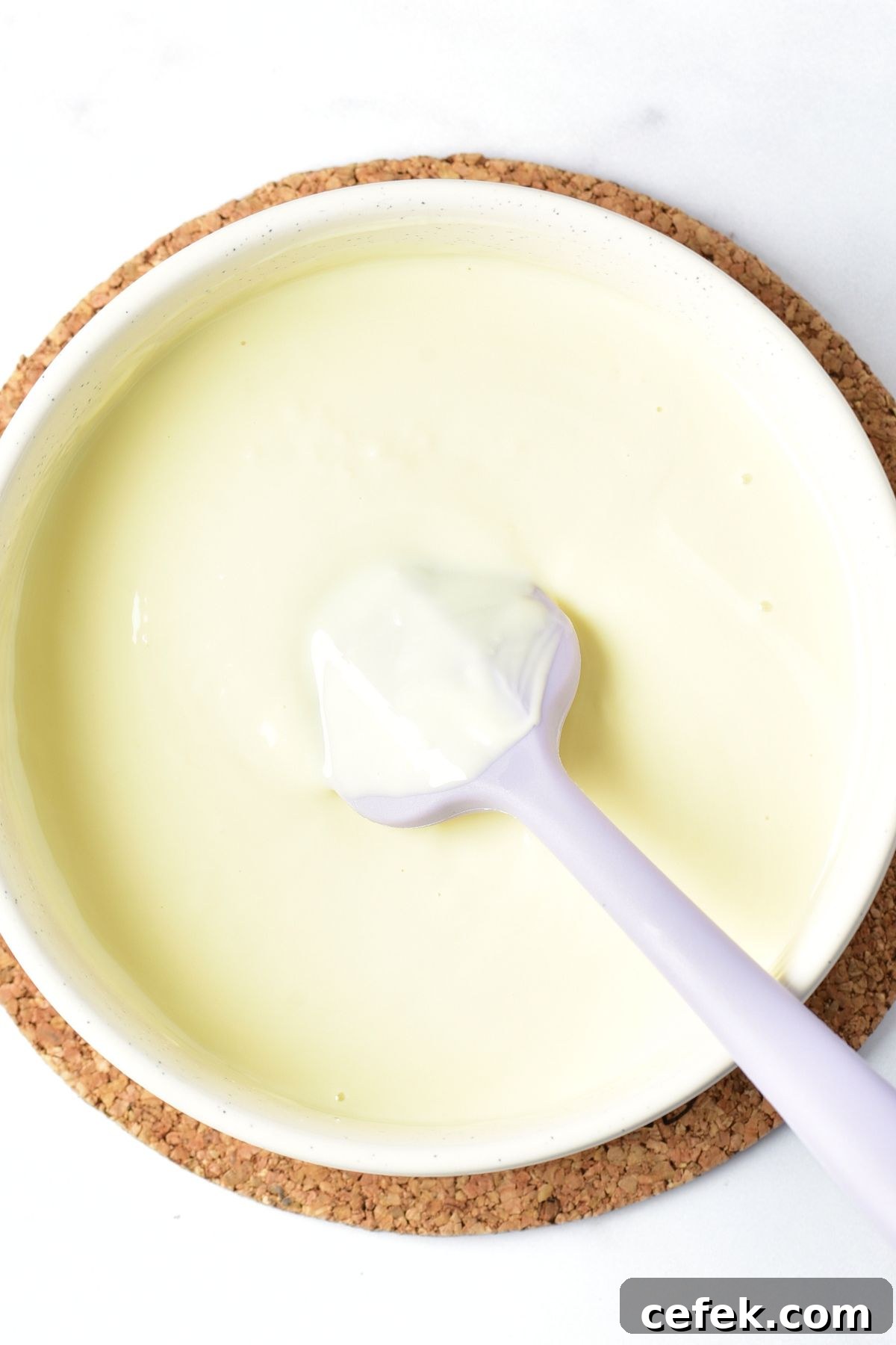 A spatula in a bowl of melted white chocolate