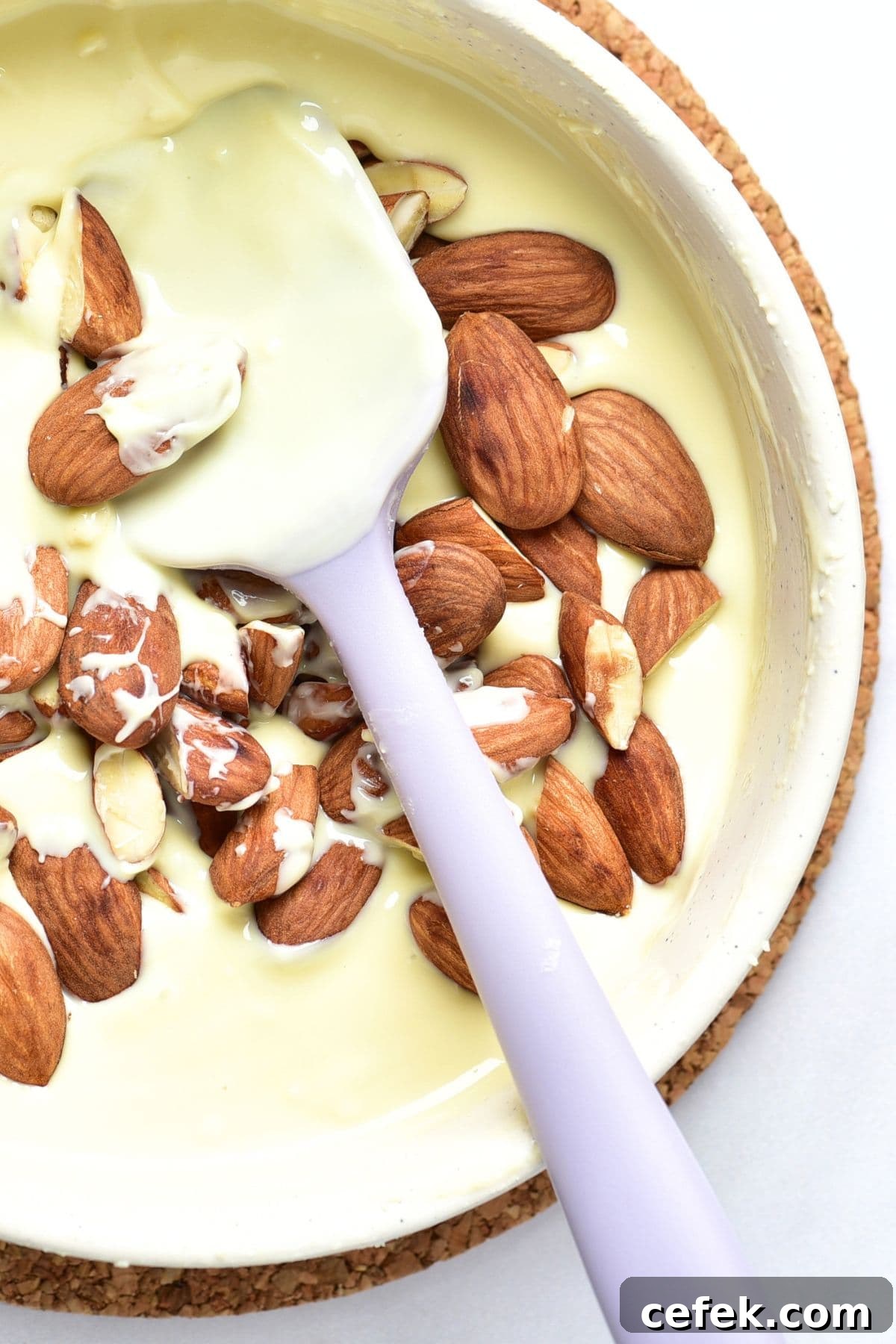 Folding whole almonds into melted white chocolate