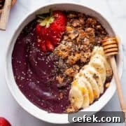 Healthy, high protein acai bowl topped with fresh strawberries, granola, sliced banana, chia seeds, and a drizzle of honey.
