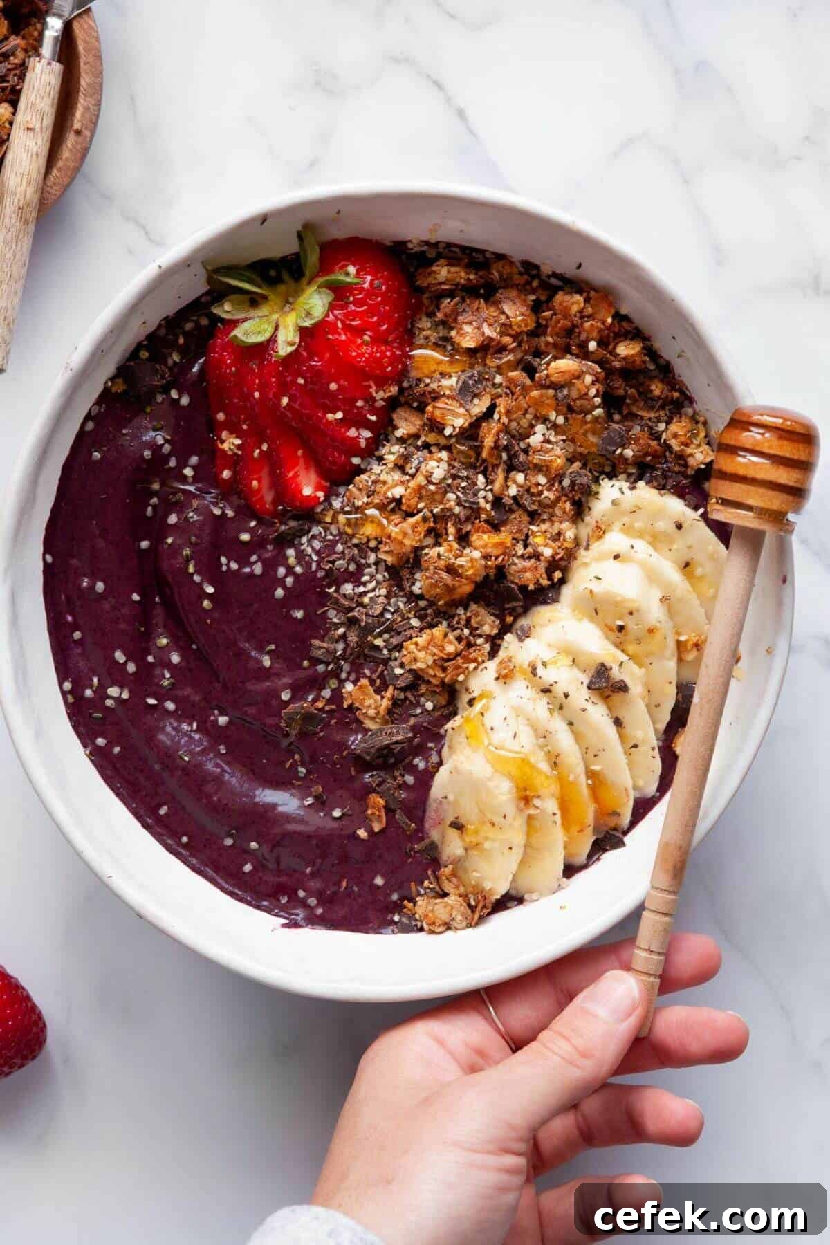 Homemade high protein acai bowl topped with strawberries, granola, banana slices, and chia seeds.