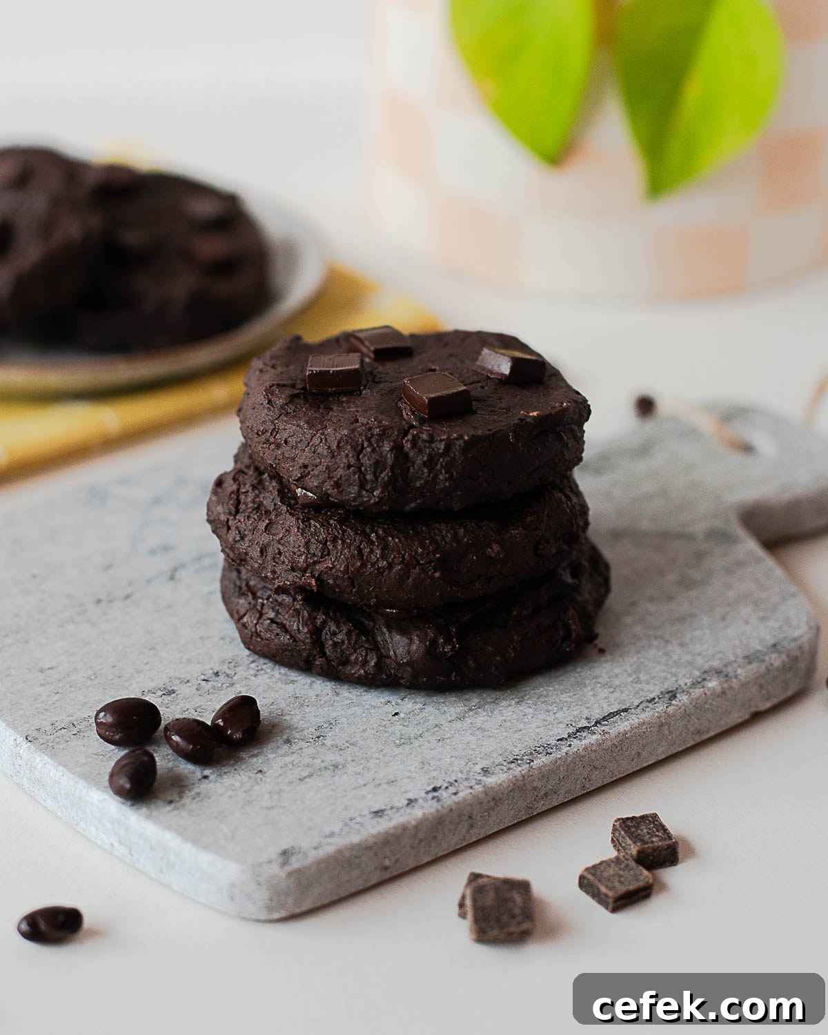 Stack of fudgy chocolate black bean cookies on a stone board with chocolate pieces