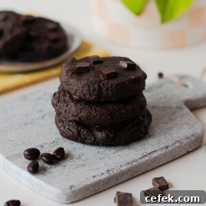 Stack of fudgy chocolate black bean cookies on a stone board with chocolate pieces