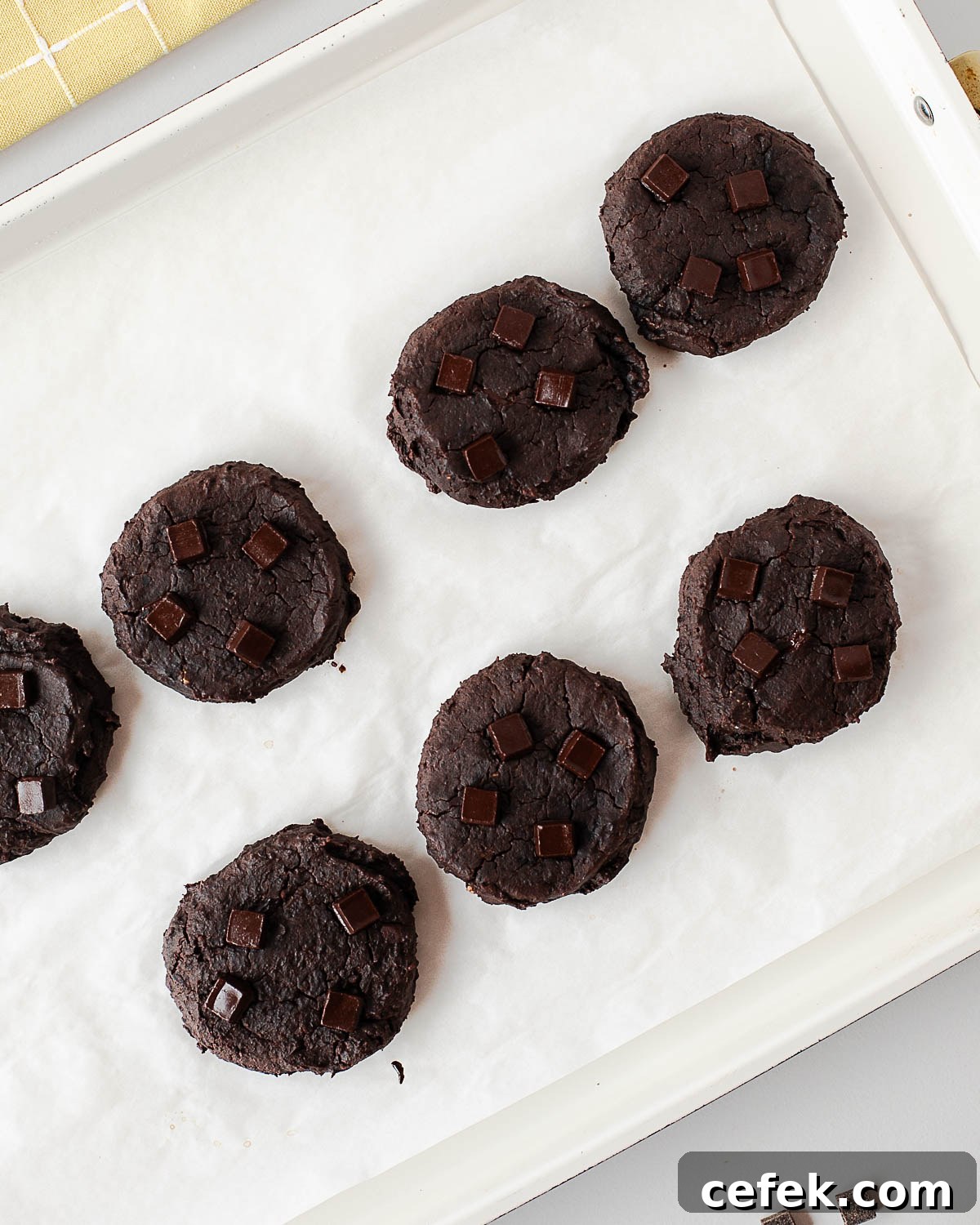 Baked black bean cookies with dark chocolate chunks on a baking tray