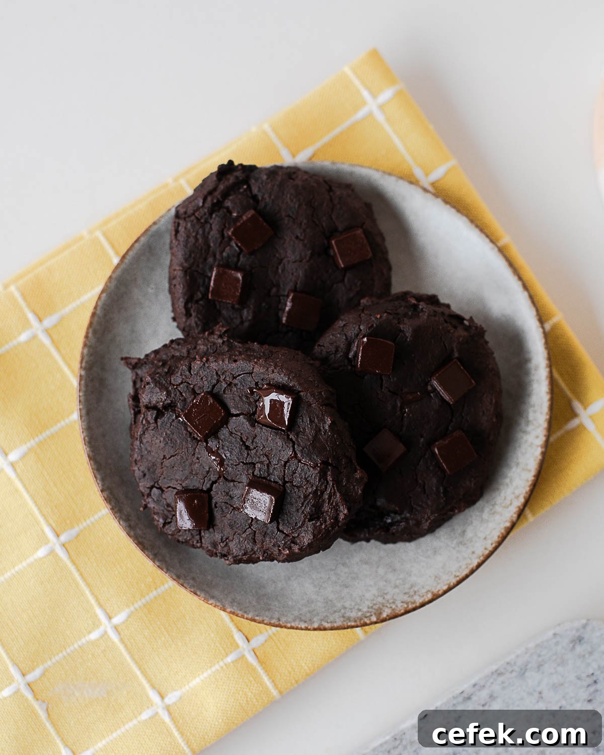 Plate of baked black bean cookies with chocolate chunks on a yellow cloth