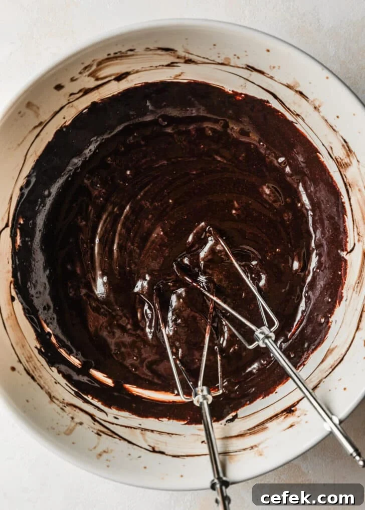 A white bowl with brownie batter and beaters.