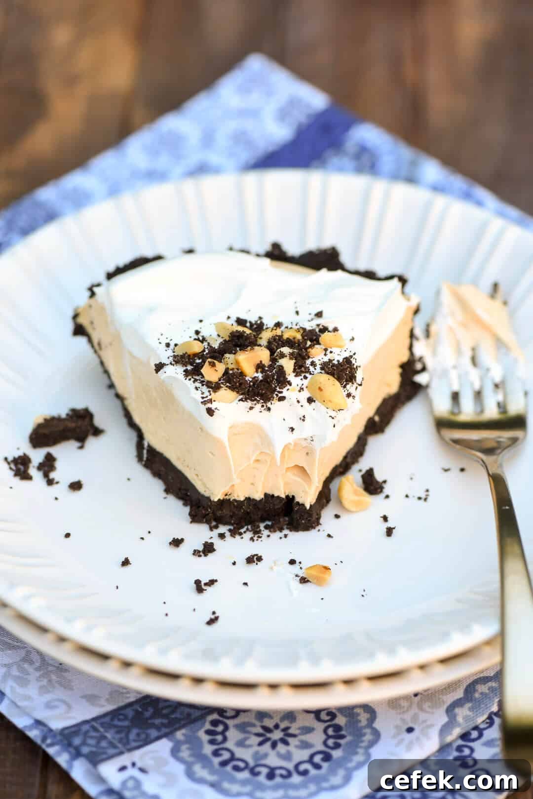 A slice of pie with a couple of bites taken out of it sits on a white plate on a blue cloth.