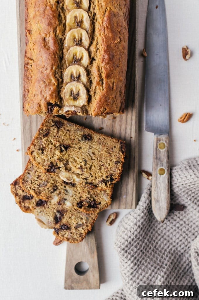 Loaf of banana bread on cutting board with slices being cut out
