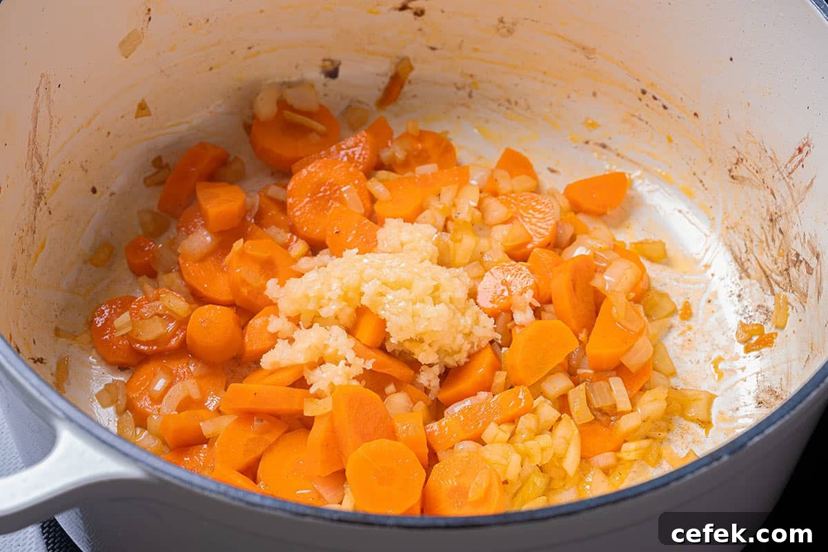 carrots and diced onion sauted in a blue pot