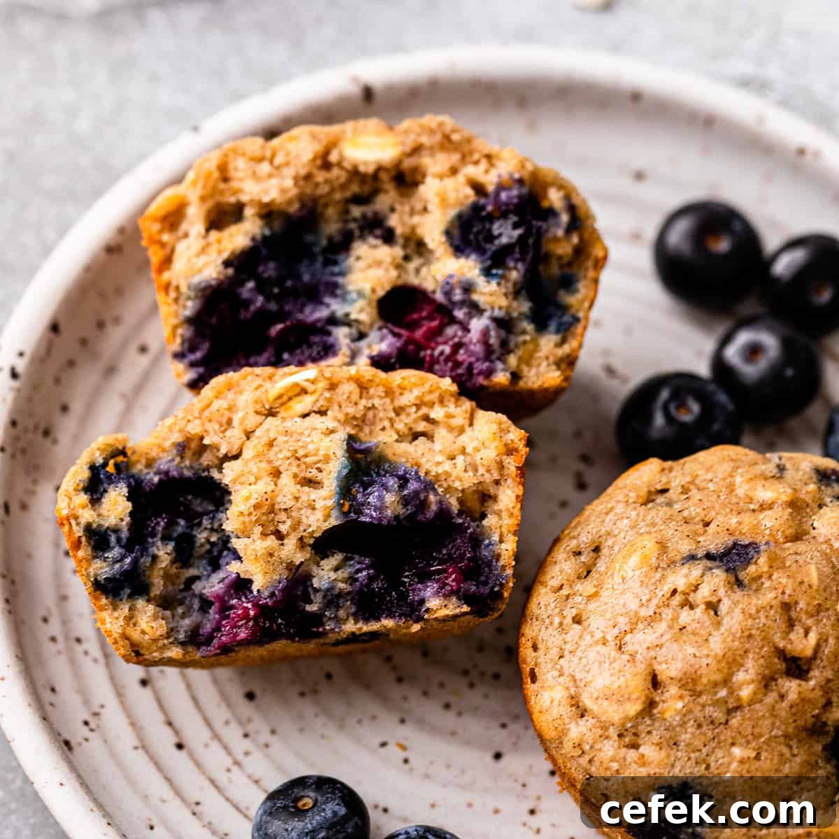 2 Blueberry Oatmeal Muffins on a plate, one cut in half 