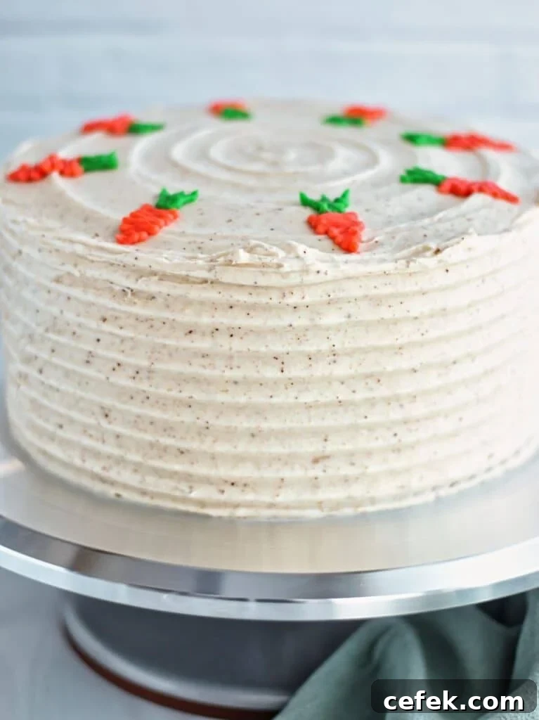 whole gluten free carrot cake on stainless steel cake stand with green towel in the forefront.